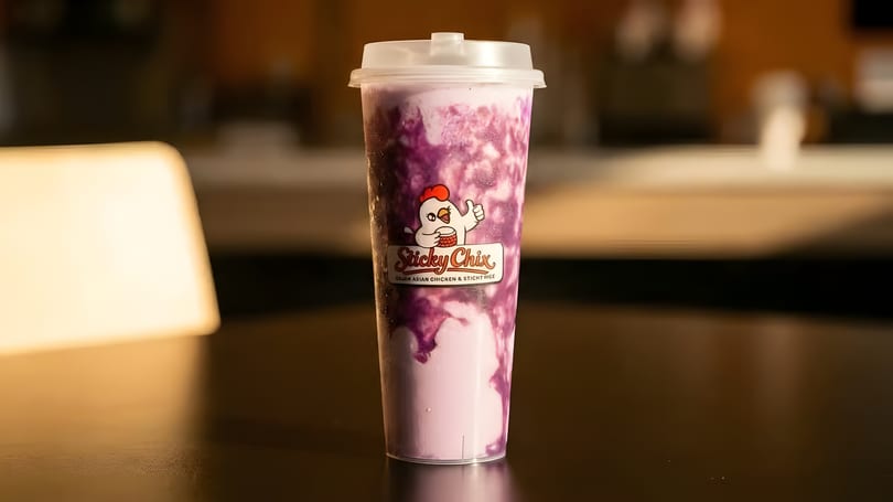 A purple and white swirled drink in a clear plastic cup with the Sticky Chix logo.
