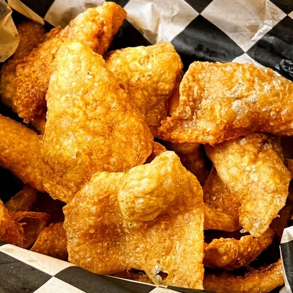 Crispy fried pork rinds in a basket lined with black and white checkered paper.