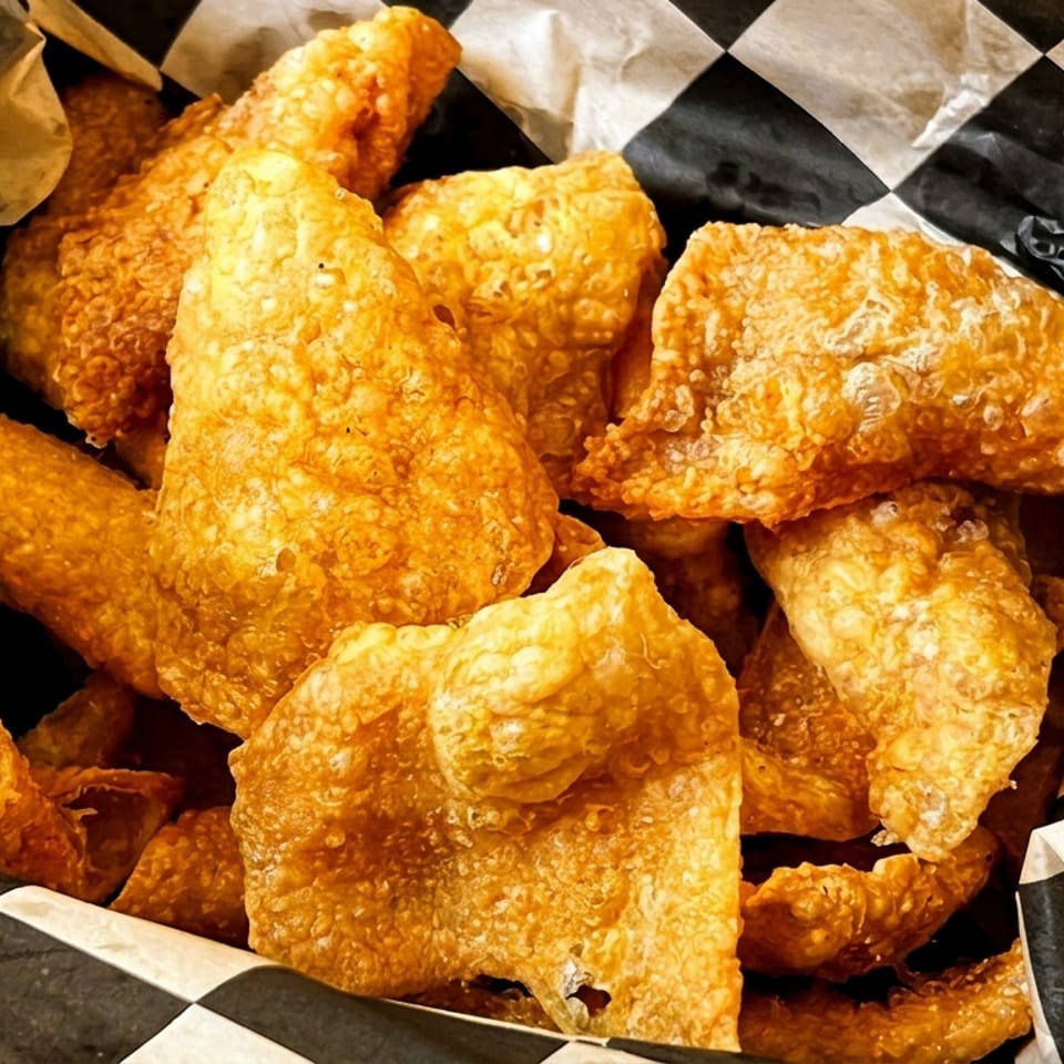 Crispy fried pork rinds in a basket lined with black and white checkered paper.