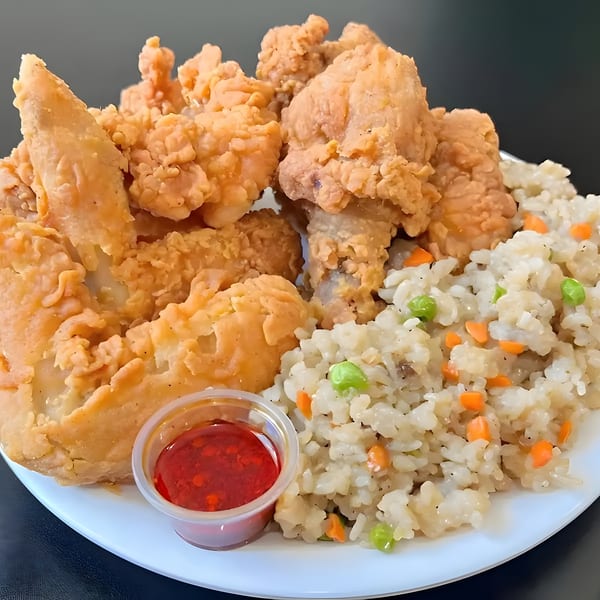Crispy fried chicken pieces and wings with a side of fried rice and sweet chili sauce.